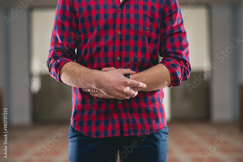 Young Muslim standing in prayer with hands on belly