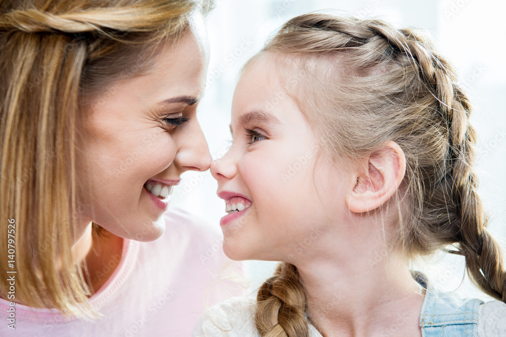 Close-up portrait of happy mother and daughter looking at each other Close-up portrait of happy mother and daughter looking at each other