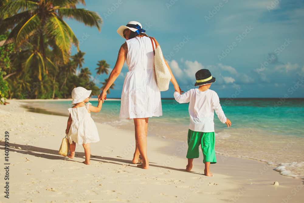 mother with little son and daughter walk on beach