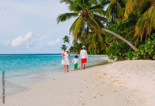 family with kids walking on tropical beach