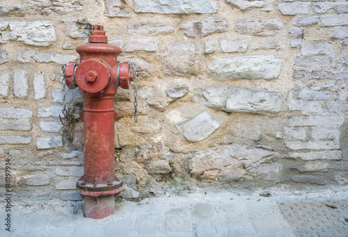Close Up to a red fire hydrant with stone wall background.