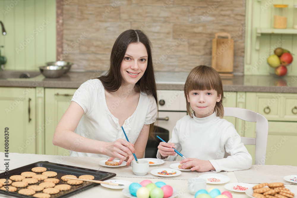 Fototapeta premium Młoda mama i jej synek wspólnie pieczą i dekorują babeczki