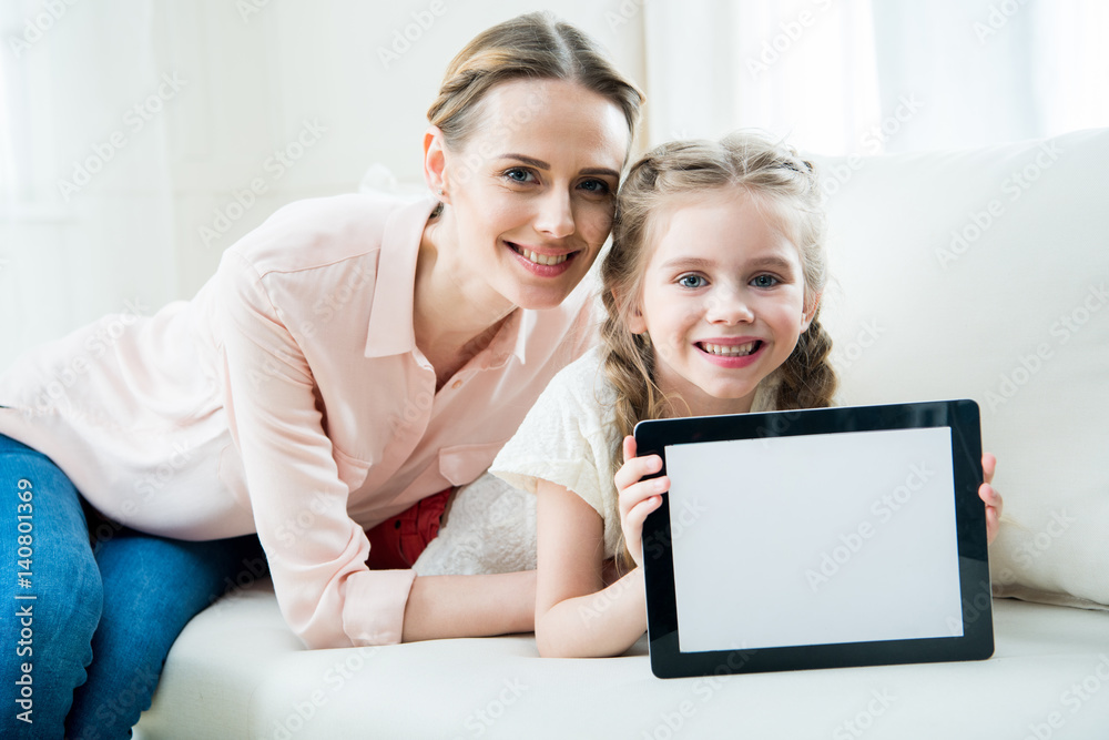 portrait of smiling mother and daughter showing digital tablet portrait of smiling mother and daughter showing digital tablet