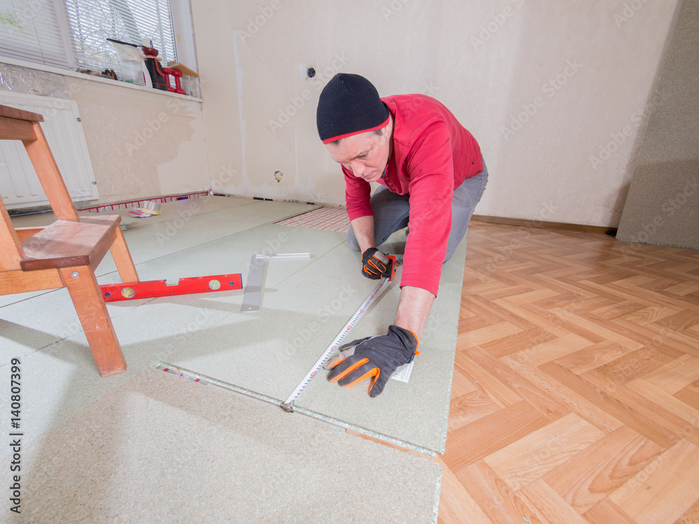 Repair in the apartment. The man puts the floor covering in the room. Repair in the apartment. The man puts the floor covering in the room.