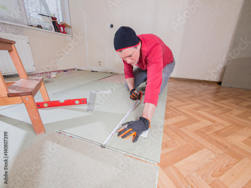 Repair in the apartment. The man puts the floor covering in the room.