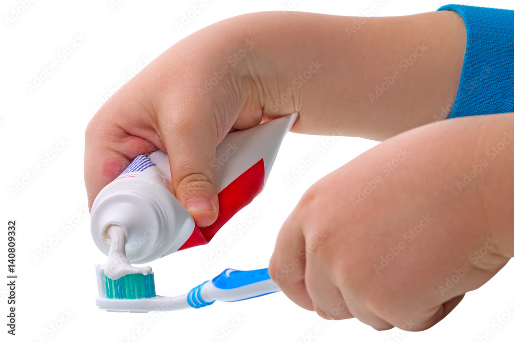 Child  squeezes the toothpaste on the toothbrush