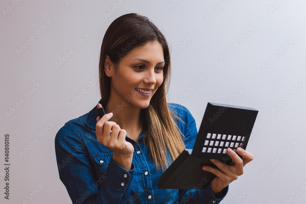 Young beautiful woman making make-up with hand mirror Young beautiful woman making make-up with hand mirror