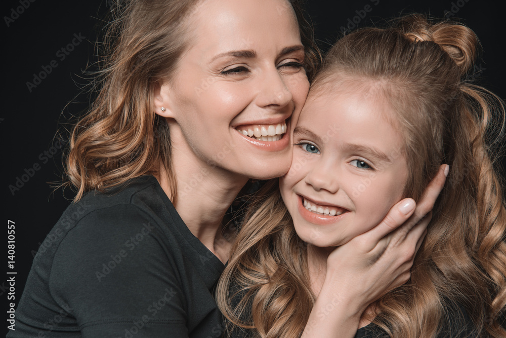 portrait of stylish daughter and mother smiling and hugging on black portrait of stylish daughter and mother smiling and hugging on black