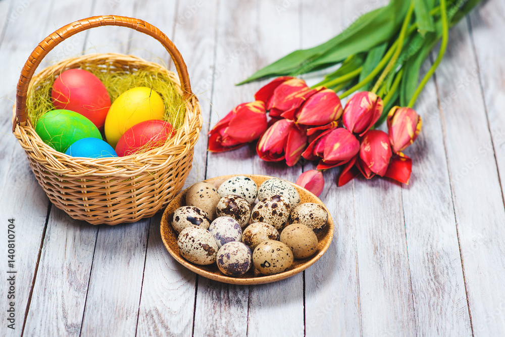 Easter background. Colored easter eggs and red tulips on wooden background. Selective focus.