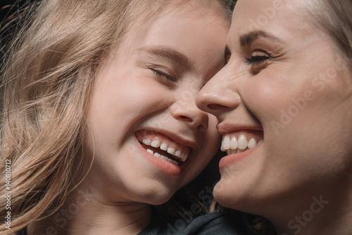 portrait of daughter and mother laughing on black
