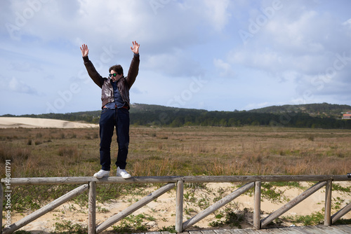 Un hombre joven a punto de caer haciendo equilibrios en una valla en las Dunas de Corrubedo photo