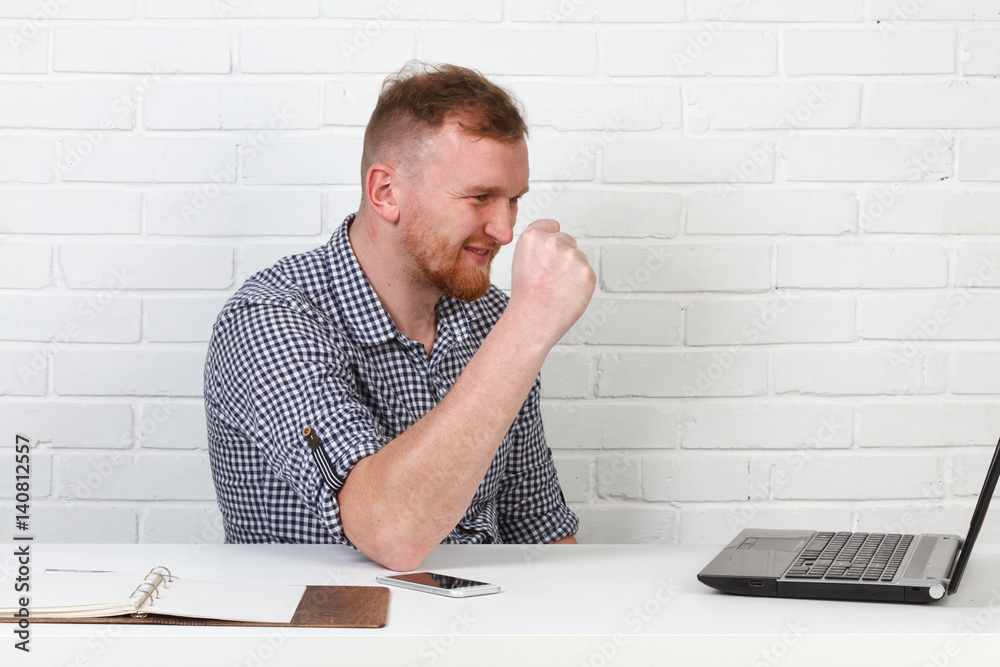 Businessman sitting at the table and working on the computer. It solves important business tasks. He is successful and well-trained. He alone on a white background. Businessman sitting at the table and working on the computer. It solves important business tasks. He is successful and well-trained. He alone on a white background.