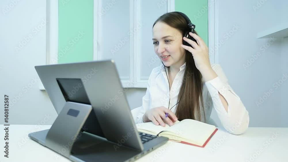 Young business woman with headphones carries a meeting on the video call. Young business woman with headphones carries a meeting on the video call.