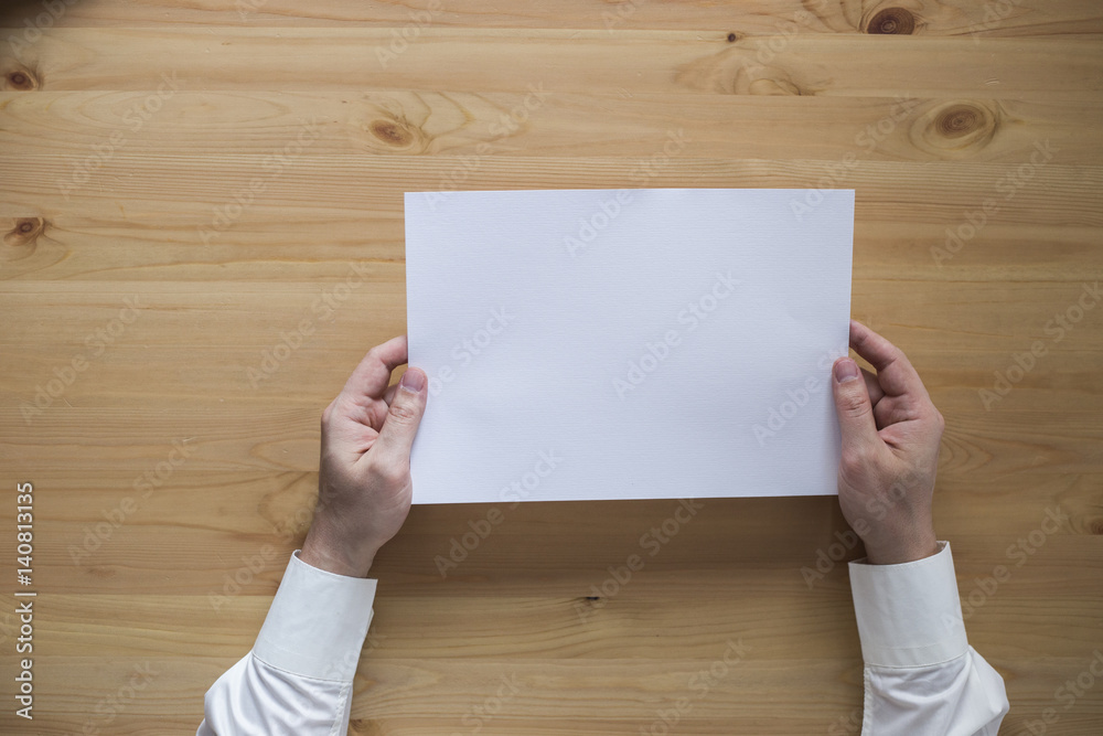 Obraz premium a sheet of paper on the desk and hands, the handle, top view,