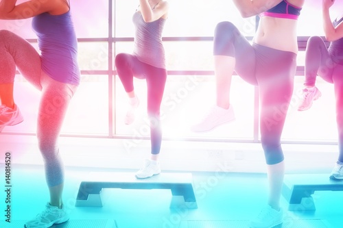 Fotografie Composite image of women raising their legs while doing aerobics