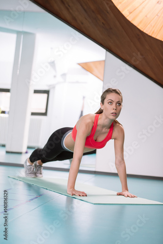 Sporty woman doing plank exercise in gym