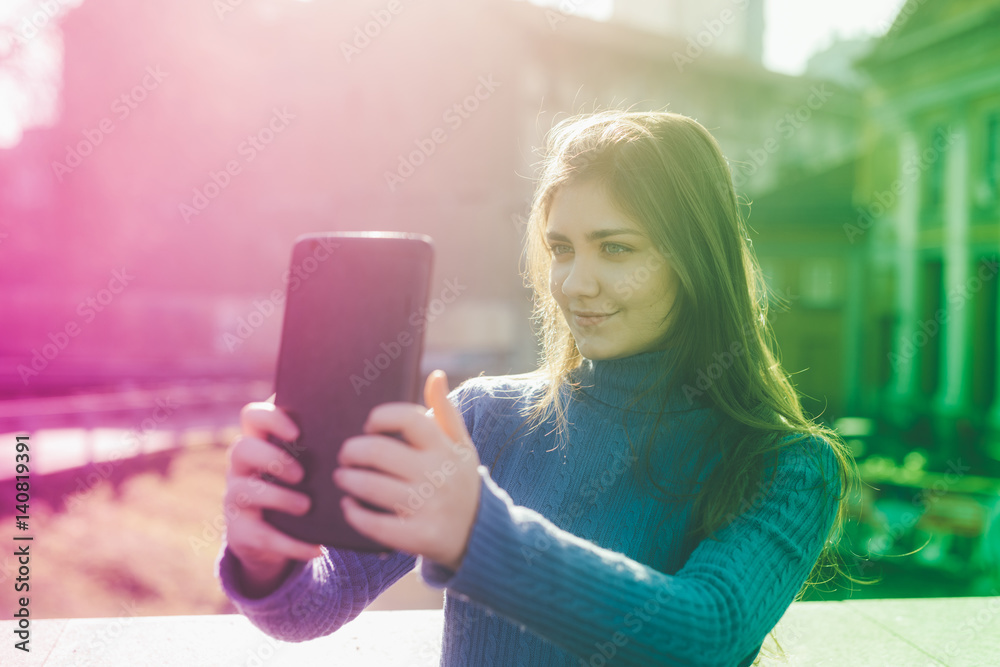 Smiling young woman taking selfie on street