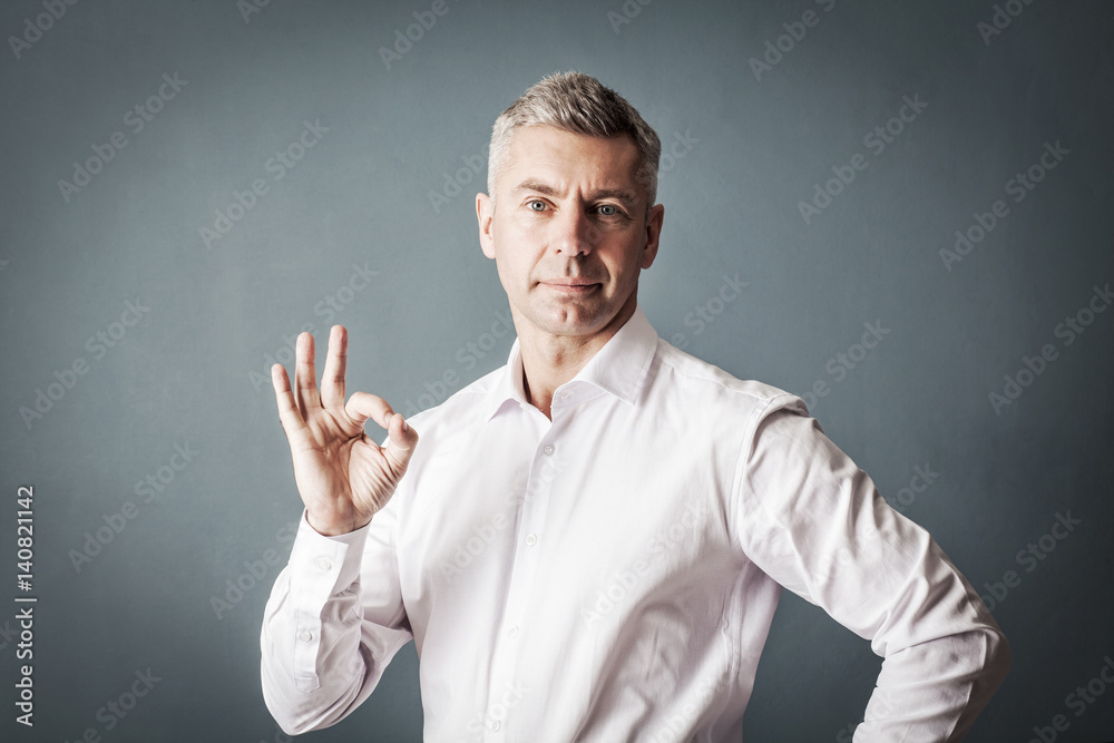 Businessman in white shirt shows a sign ok hands