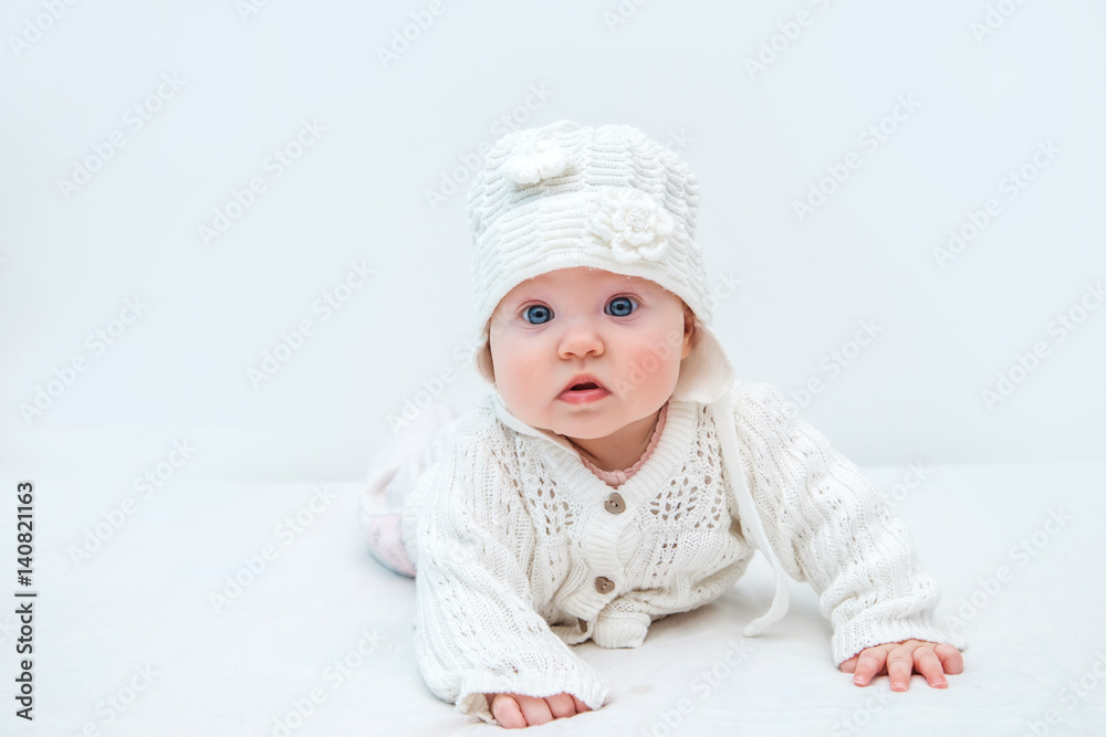 Cute baby in white knitted hat and sweater on a white background. Cute baby in white knitted hat and sweater on a white background.