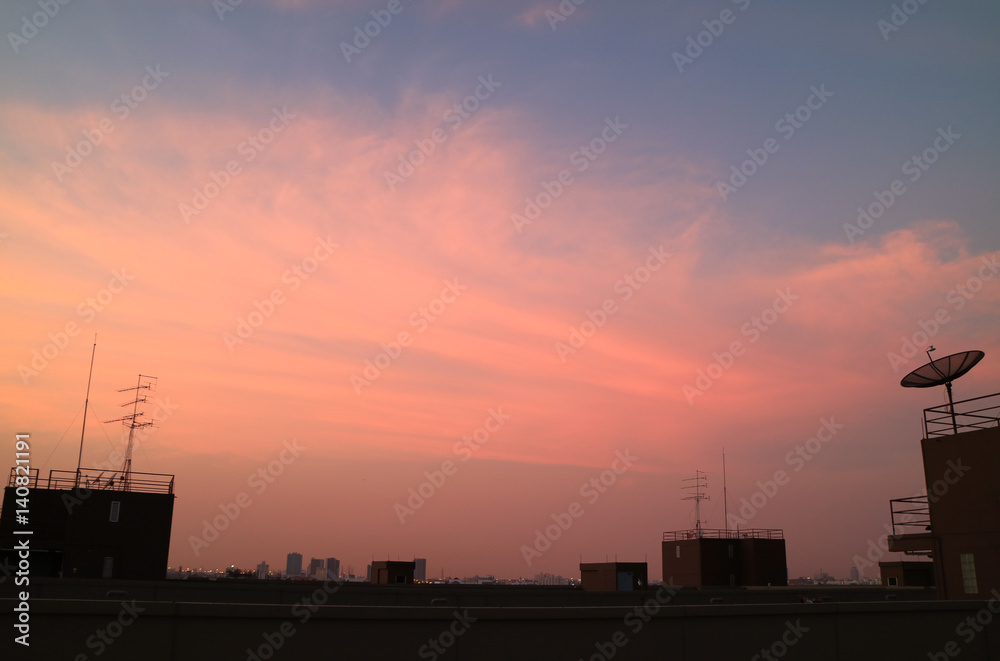 Silhouette of Modern Building Rooftops and Satellite Dish with Pink and Blue Sky in the Background 