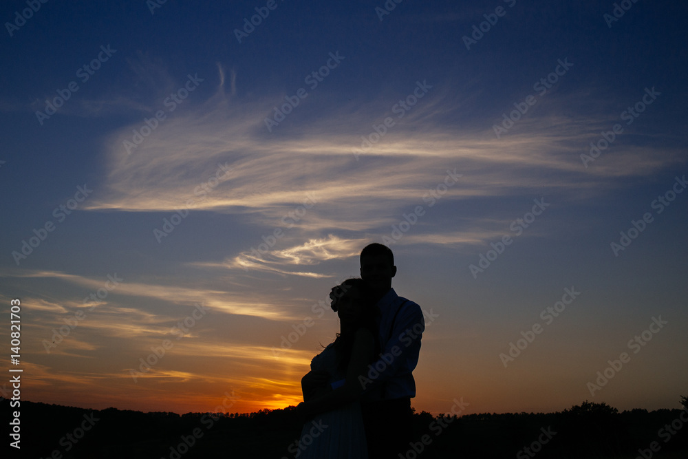 Silhouettes of a loving couple hugging at sunset