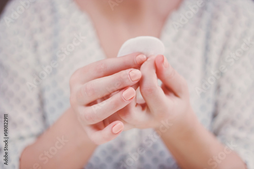 Woman is cleaning nail polish with the cotton pad