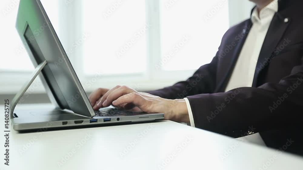 Businessman in white shirt and jacket is typing on a laptop in the office. Businessman in white shirt and jacket is typing on a laptop in the office.
