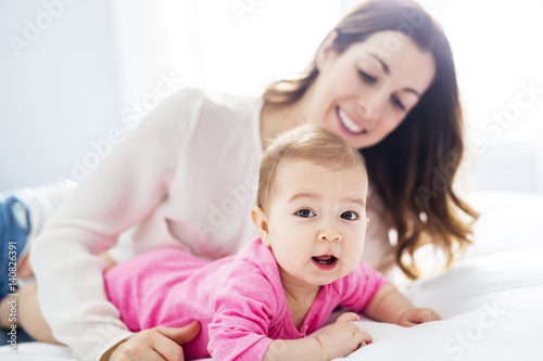 Mother and baby child on a white bed.