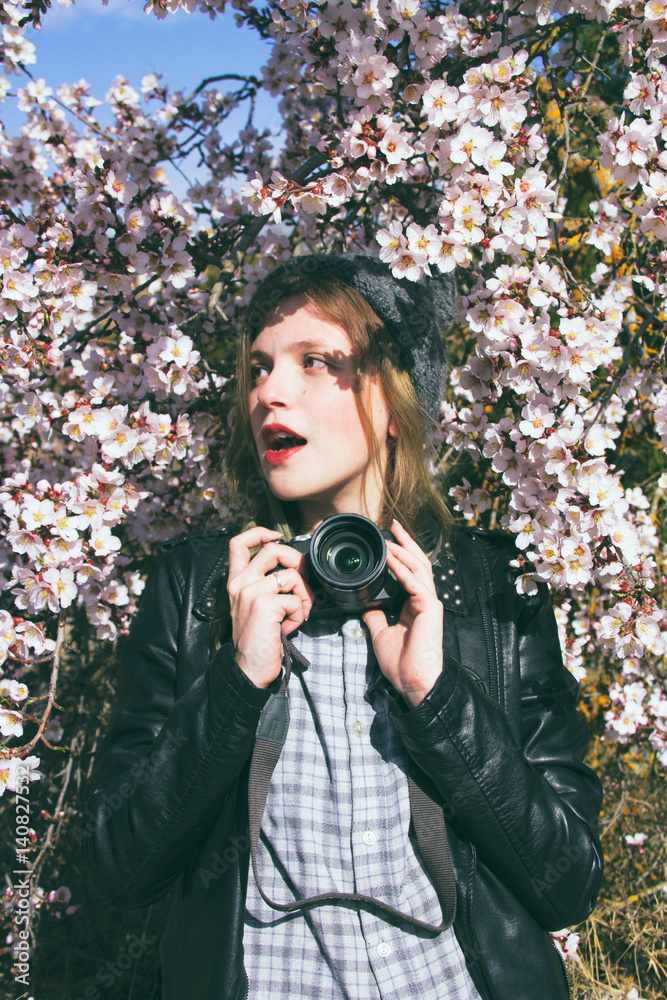 Fotógrafa joven con ropa urbana tomando fotografías cerca de un árbol en  flor en primavera foto de Stock | Adobe Stock