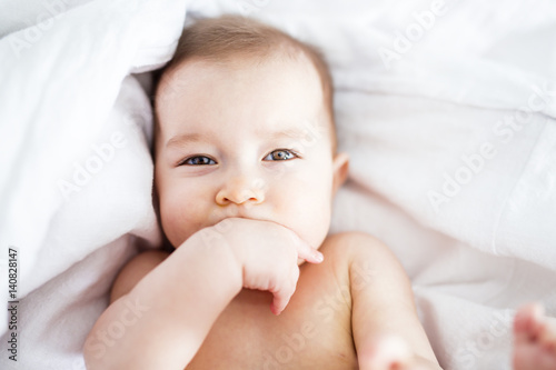 baby girl lying on white sheet