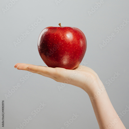 Woman on diet with an apple in the hand against gray background