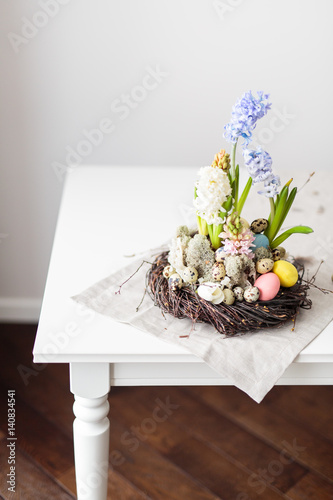 Flower arrangement in a nest with easter eggs on a white table