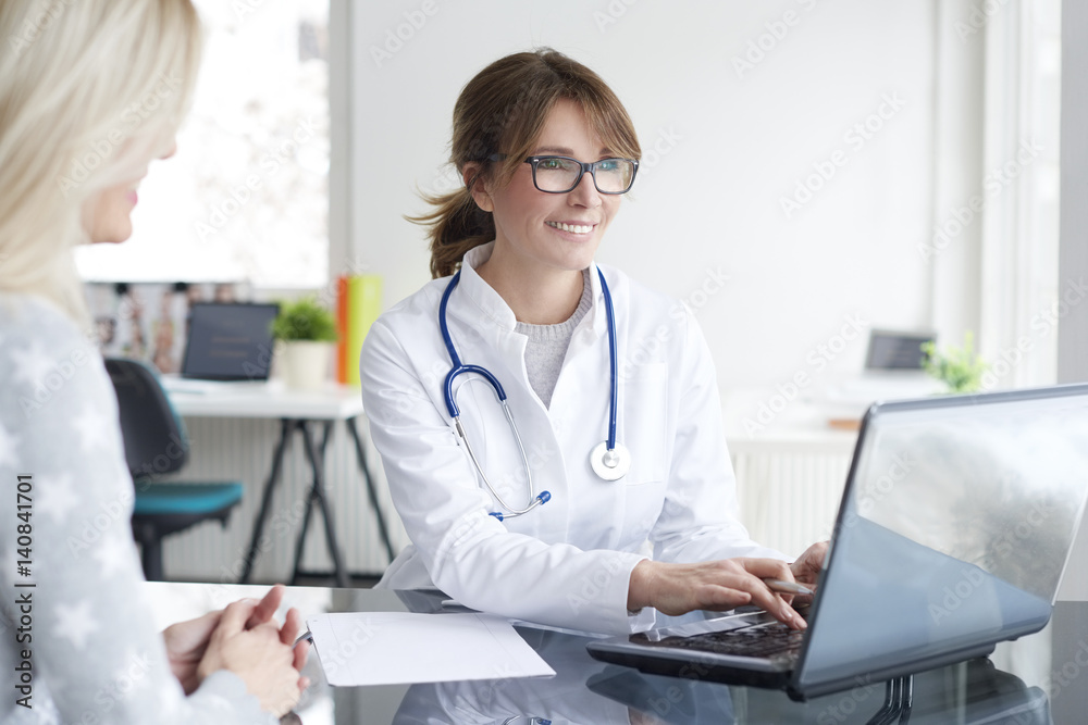 Doctor and her patient. Shot of a middle aged female doctor sitting in front of laptop and consulting with her patient. Doctor and her patient. Shot of a middle aged female doctor sitting in front of laptop and consulting with her patient.