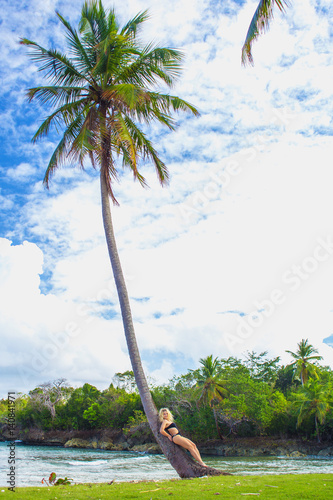 young girl scrambling on the high palm tree. Tropical landscape, caribbean view © Sergey