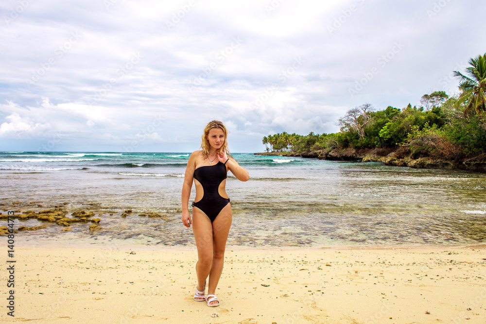 Young happy girl in black bikini  near the wild shore. Samana, Dominican Republic