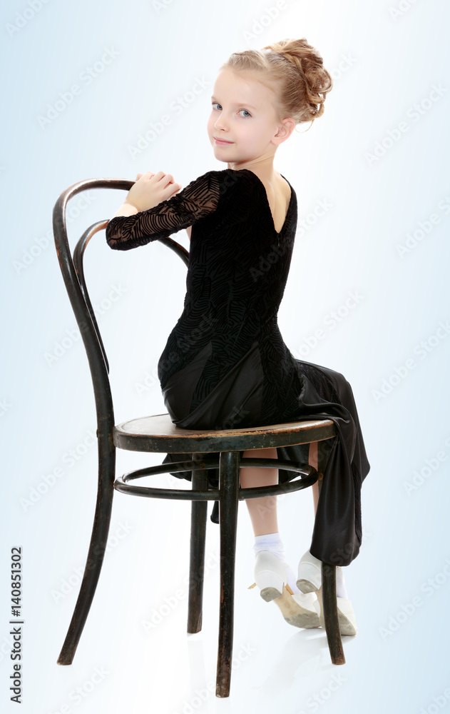 Fototapeta premium Slender little dancer posing near the old Vienna chair.