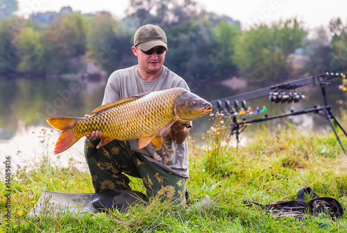 Happy angler with carp fishing trophy