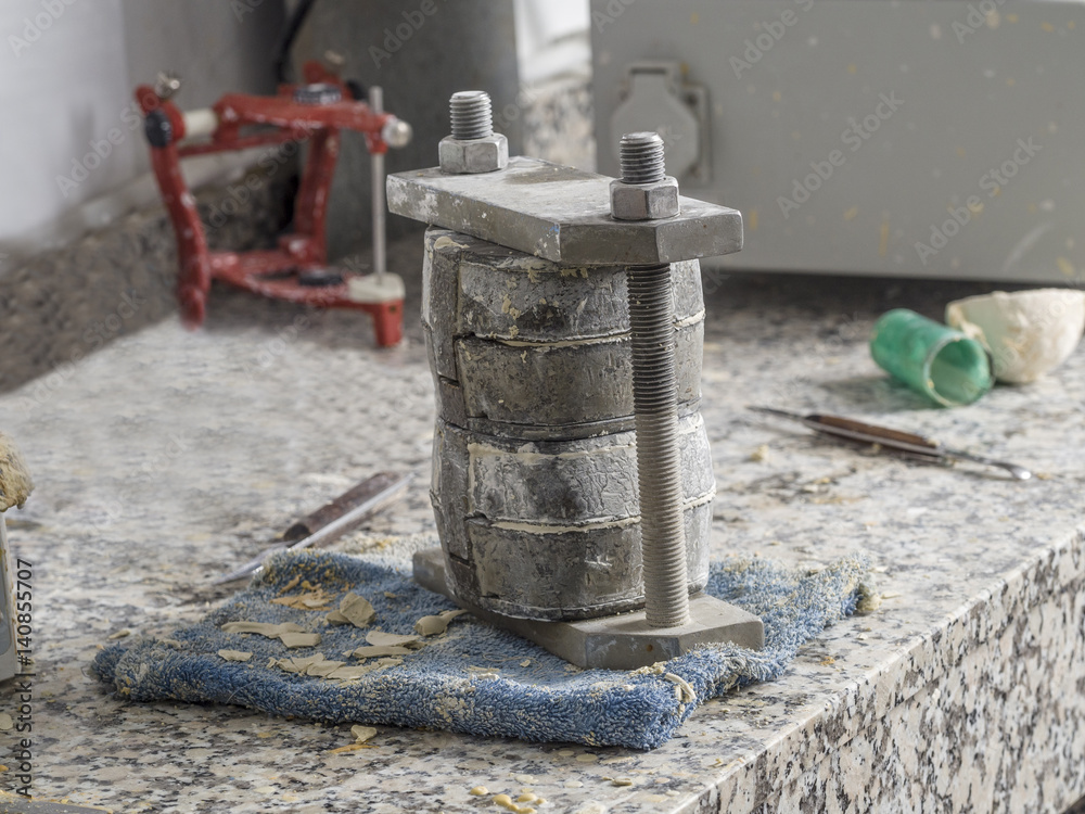 Dental technician is working with a dental flask of a complete upper on cast Dental technician is working with a dental flask of a complete upper on cast