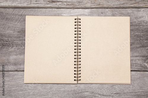 A blank recycled paper scrapbook sits on a rustic wooden background. photo