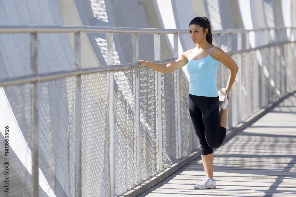 young beautiful athletic sport woman stretching after running crossing modern metal city bridge