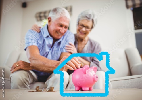 Senior couple insert coins in piggy bank against house outline