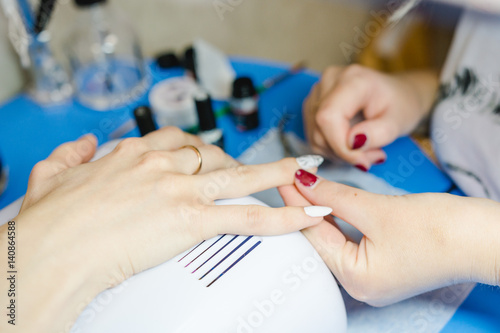 Manicure. The woman cleans and paints nails. The woman processes nails on hands a varnish. Shelak. Gel  a varnish  placing acryle on nails.