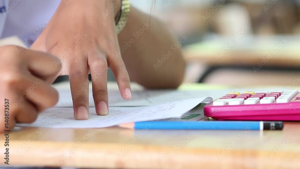 close up girl hands of student writing during the test exam with calculator in classroom close up girl hands of student writing during the test exam with calculator in classroom