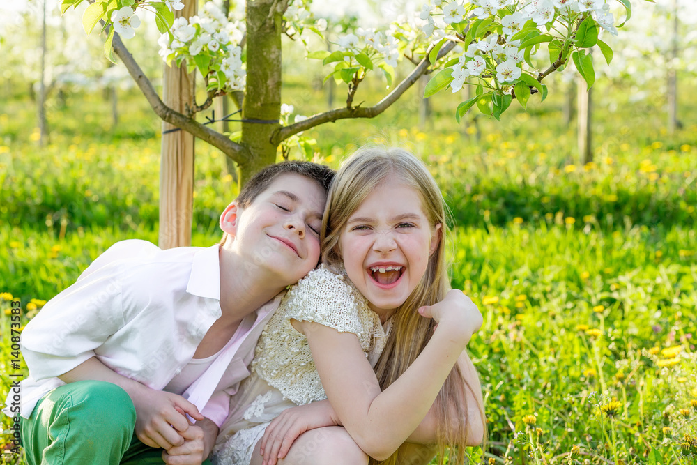  A boy and a girl are resting in a blooming garden in the spring