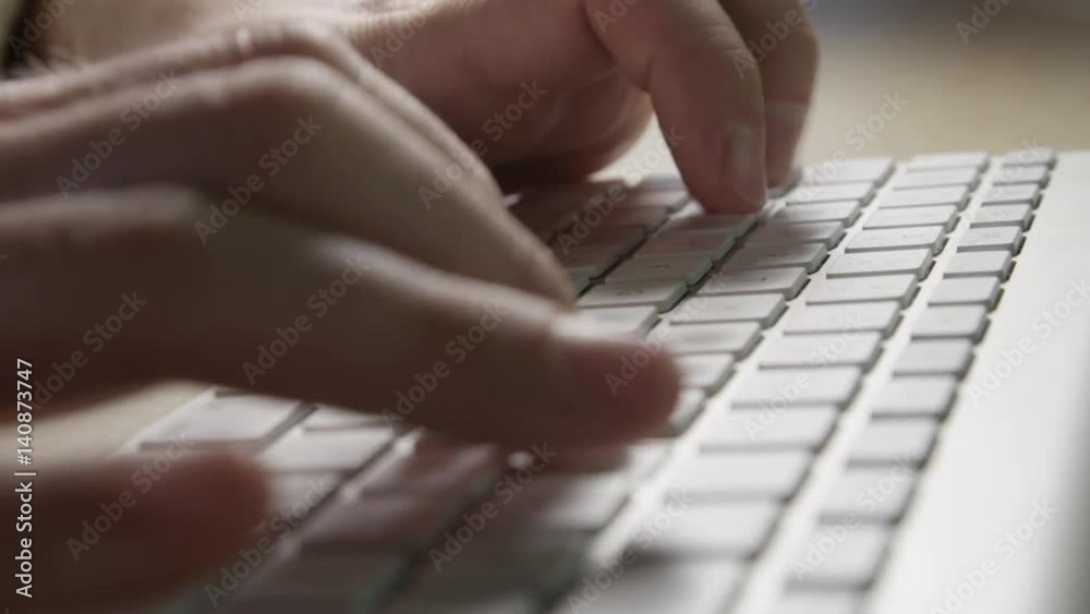 Close up DOF detail of fingers typing, pressing the buttons on modern wireless keyboard