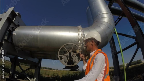 The engineer opens and closes the valve on the industrial pipeline for hot water and heating, gas, oil, resources 
