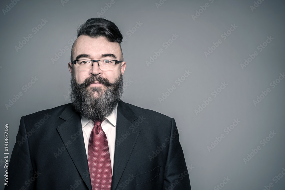 Adult bearded man in a suit and glasses on a gray background, toned Adult bearded man in a suit and glasses on a gray background, toned