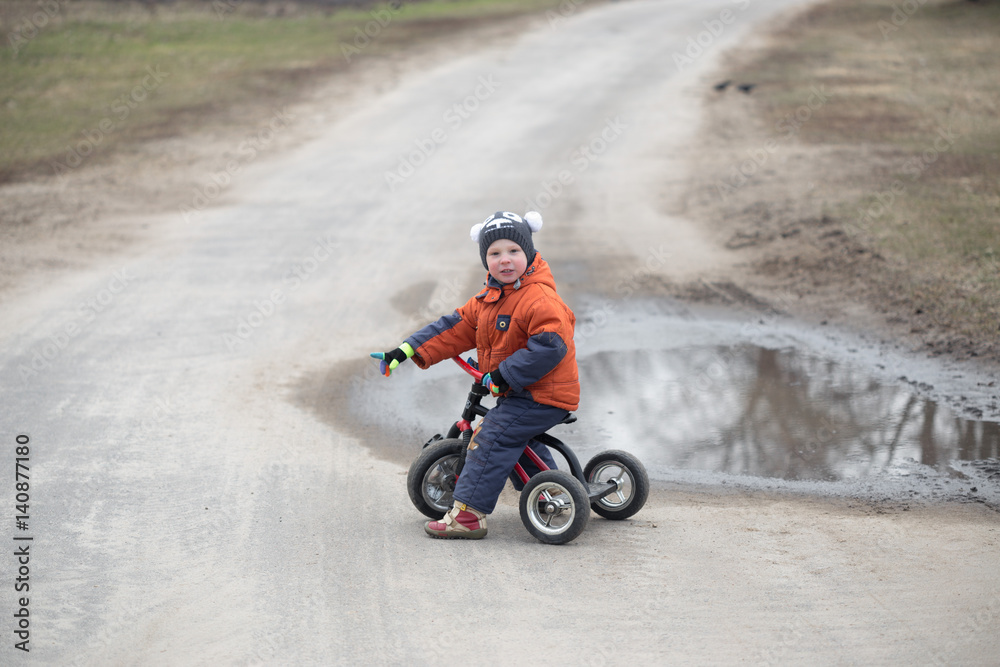 Fototapeta premium The little boy is riding a tricycle