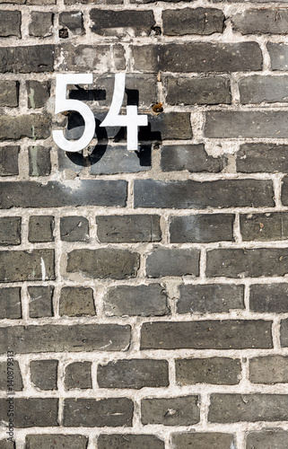 Metal house number fifty four sign on grey brick wall photo