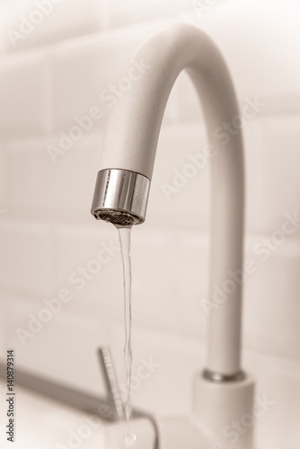 Beige faucet in the kitchen on a background of white tiles